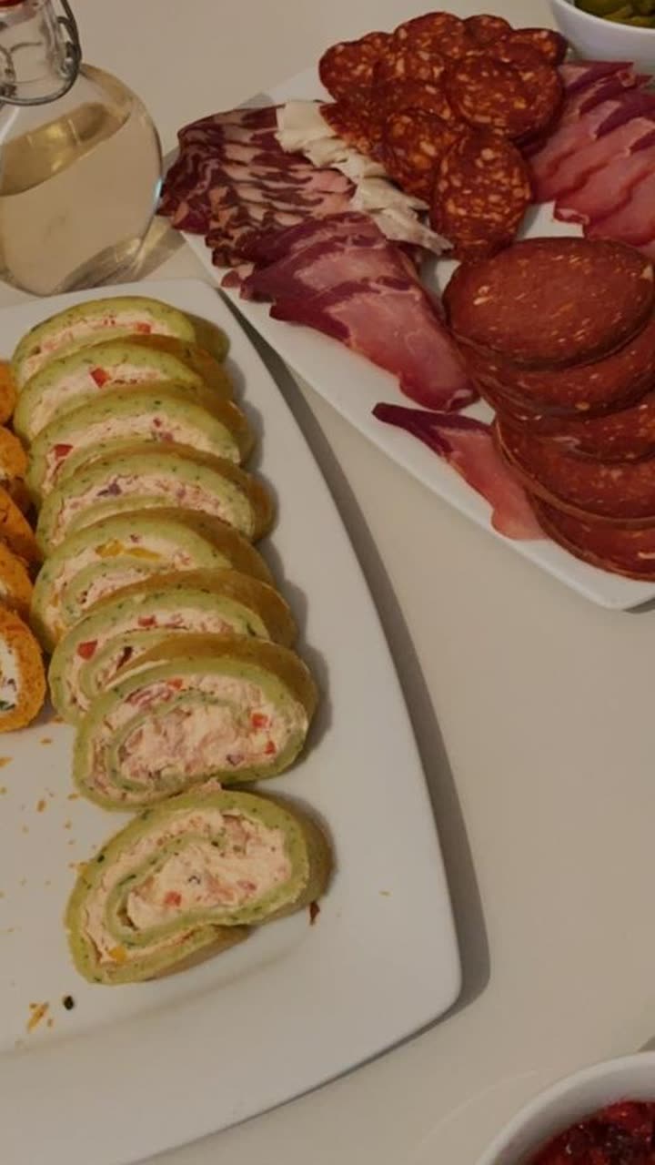 Originalfoto: Apéro-Platte mit Roulade, Rohschinken und Salami auf einem weissen Tisch
